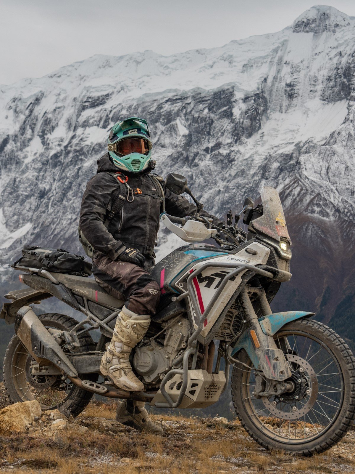 Motorcyclist with adventure motorcycle during our Nepal motorcycle tour with snow-capped mountains in the background.
